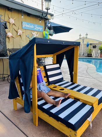Person lounging in a cabana-style poolside chair with drink holders