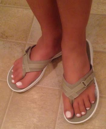 Person wearing strappy sandals on a tiled floor, showcasing a casual footwear style