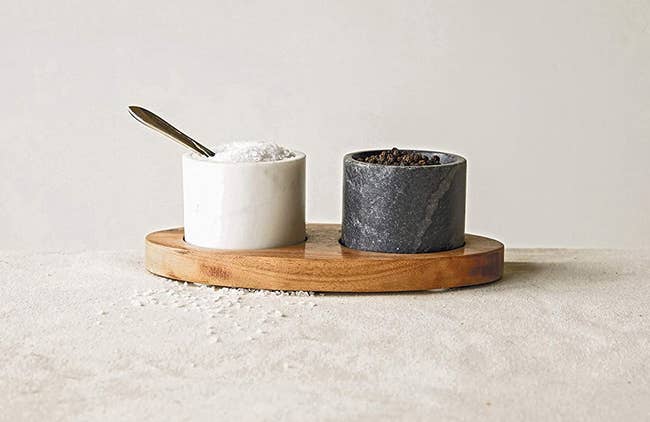 one black and one white small cup in a wood tray with a spoon in the white one