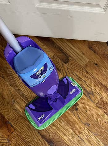 a reviewer photo of a swiffer wet jet with one of the reusable mop pads attached 