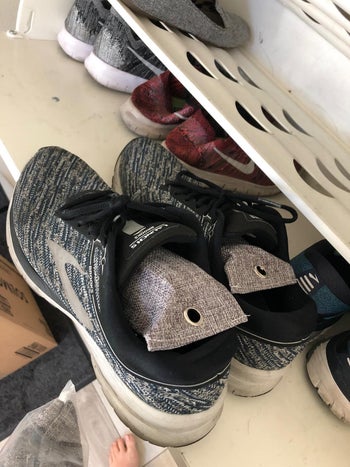 reviewer photo of two of the gray odor eliminating bags in a pair of their sneakers