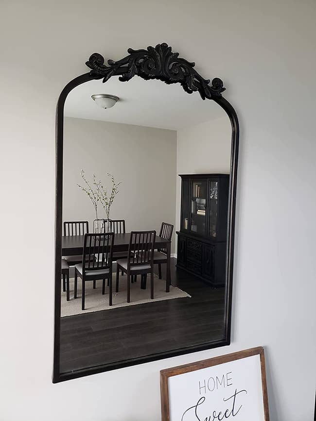 reviewer image of the black baroque inspired mirror mounted on a wall