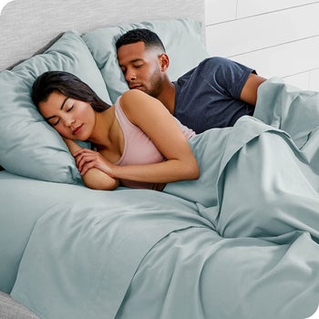 two models sleeping in a bed with the light blue sheets and pillowcases