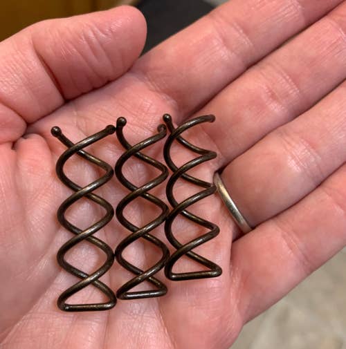 reviewer holding three of the coil pins in their palm 