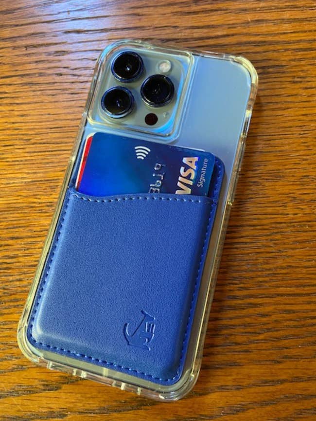 a bright blue wallet sleeve attached to the back of an iPhone holding credit cards 