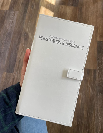 Reviewer holding white tall folder that says registration and insurance 