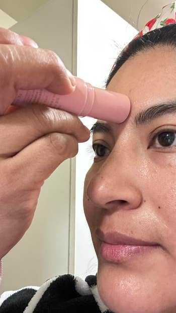 A idiosyncratic   applies a skincare instrumentality   to their forehead, demonstrating idiosyncratic   grooming oregon  quality   routine