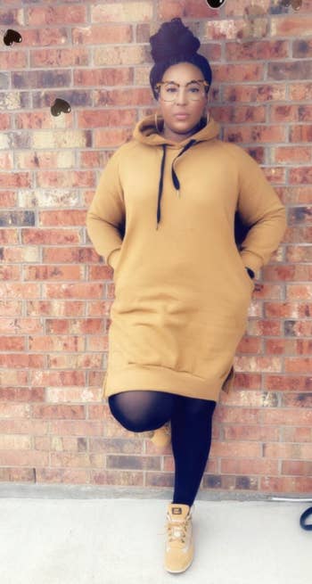 reviewer wearing the long yellow hoodie dress with black tights