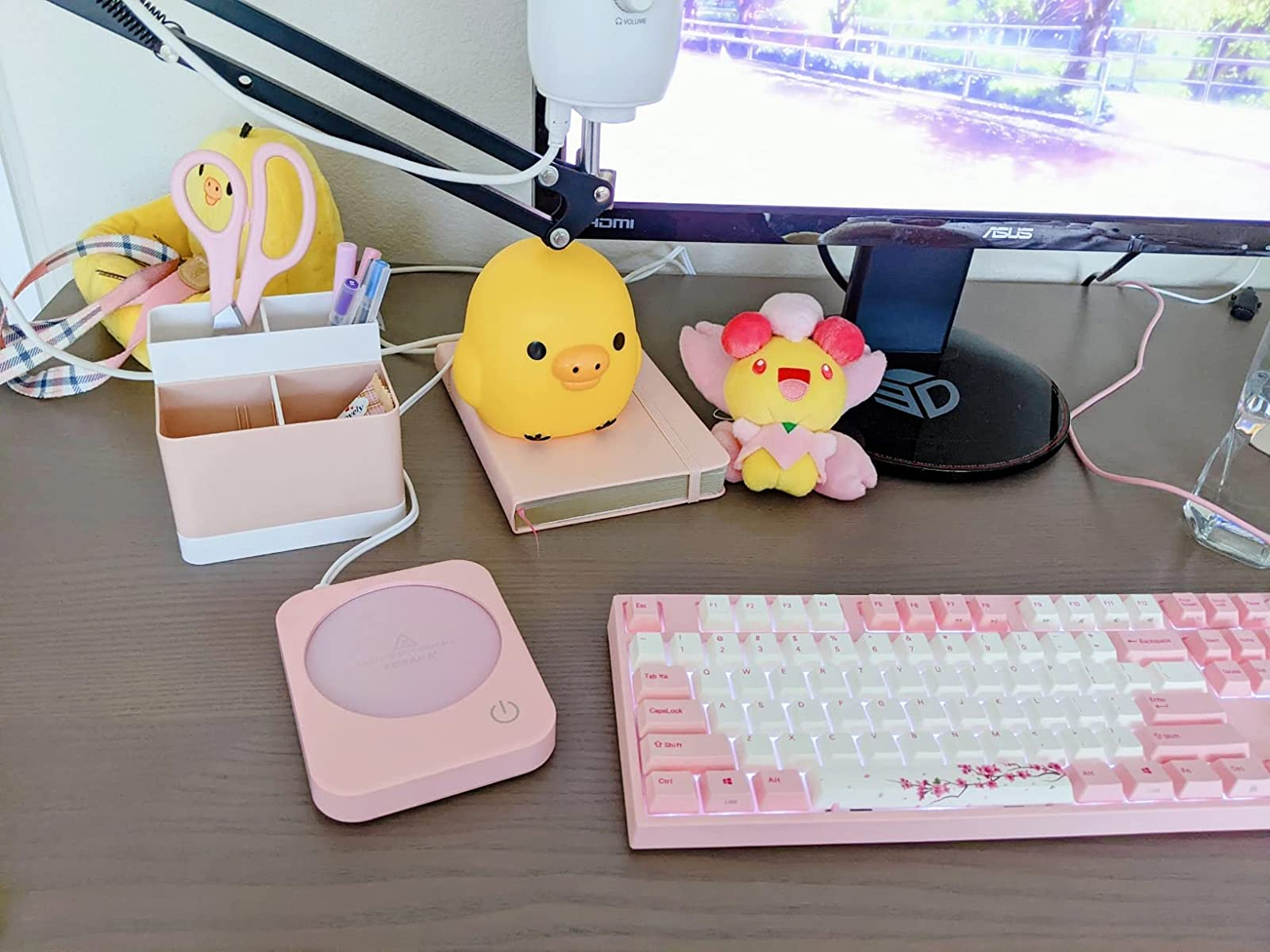 the pink coffee warmer on a work desk next to other pink accessories