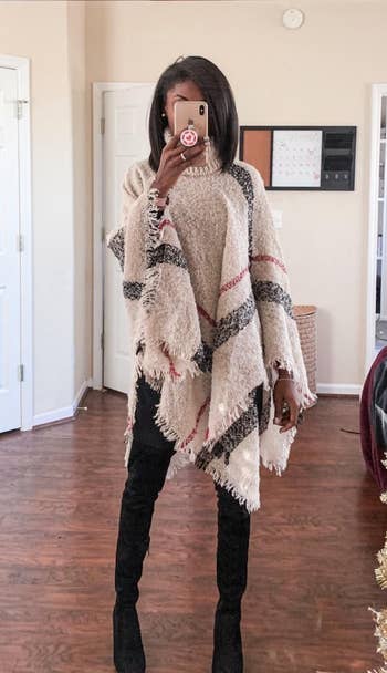 a reviewer posing in the beige plaid poncho