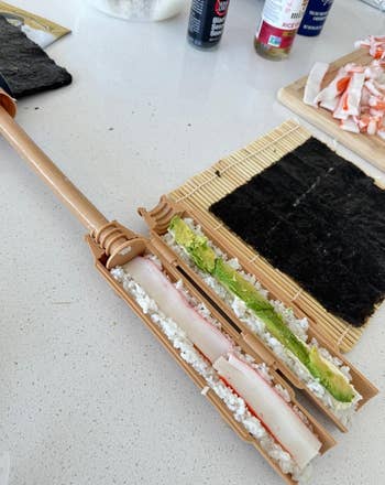 Sushi-making kit connected a antagonistic with crab, rice, and wasabi, showing sushi rolled with a bamboo mat and sushi bazooka tool