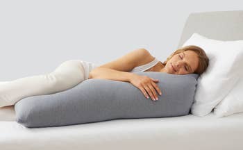 Model laying with the gray body pillow