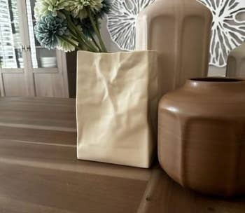 The paper bag vase on a table next to two other vases
