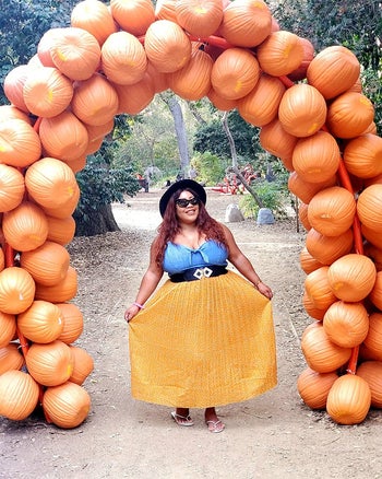 a reviewer in the skirt in yellow under an arch of pumpkins