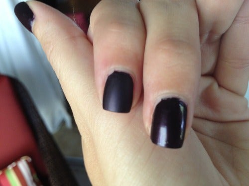reviewer's nails, one with regular shiny black polish and one matte black