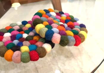 Reviewer's colorful felt ball coasters on a glass table