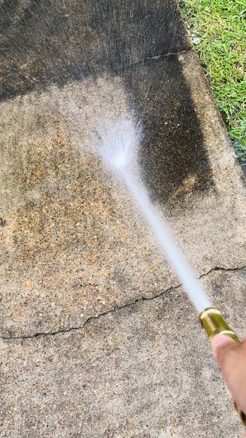 the nozzle attached to a hose being used to spray down concrete
