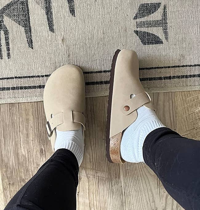 a reviewer showing the top and side view of the beige clogs