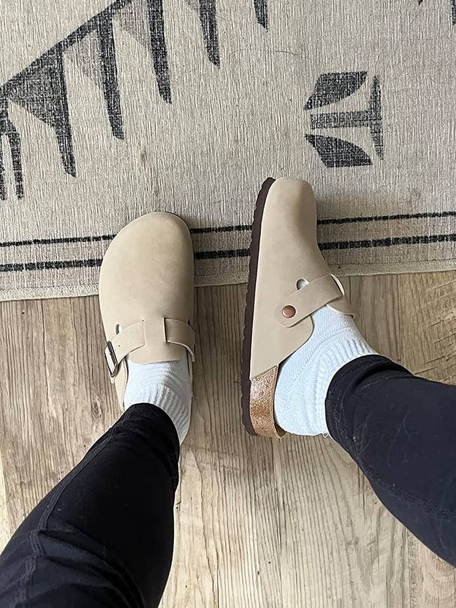 a reviewer showing the top and side view of the beige clogs