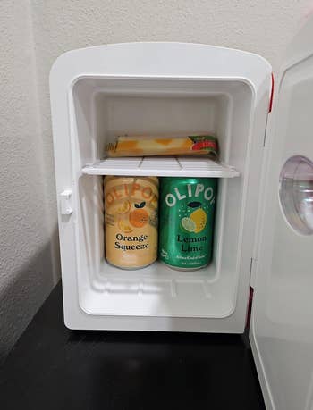 Mini fridge with orange and lemon-lime flavored drinks inside