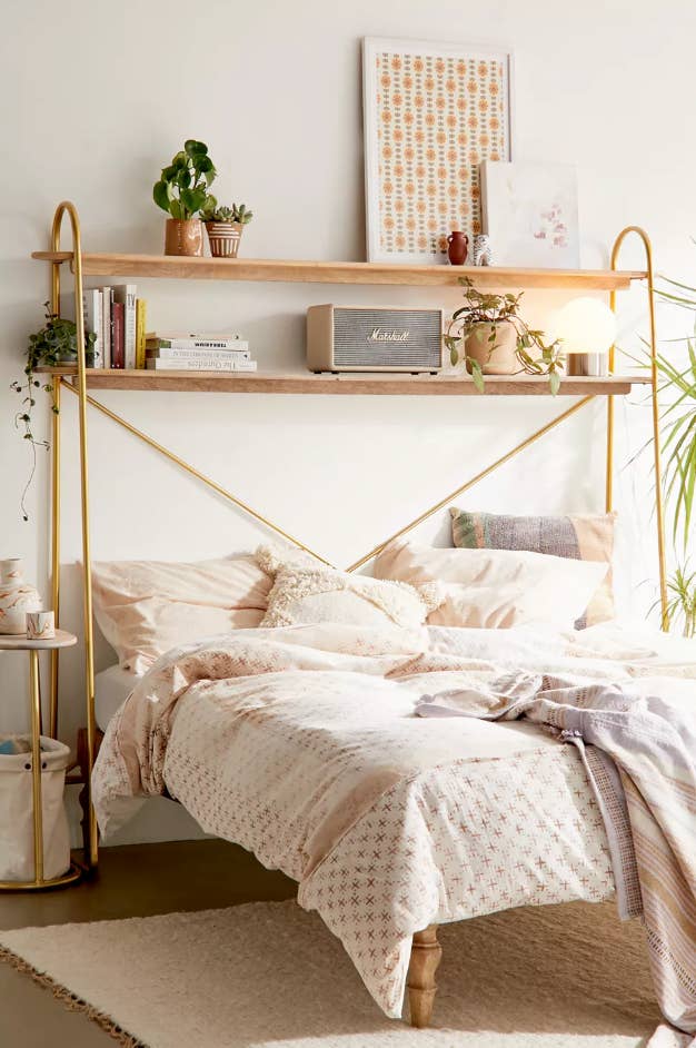 The gold metal and wood shelf over a bed
