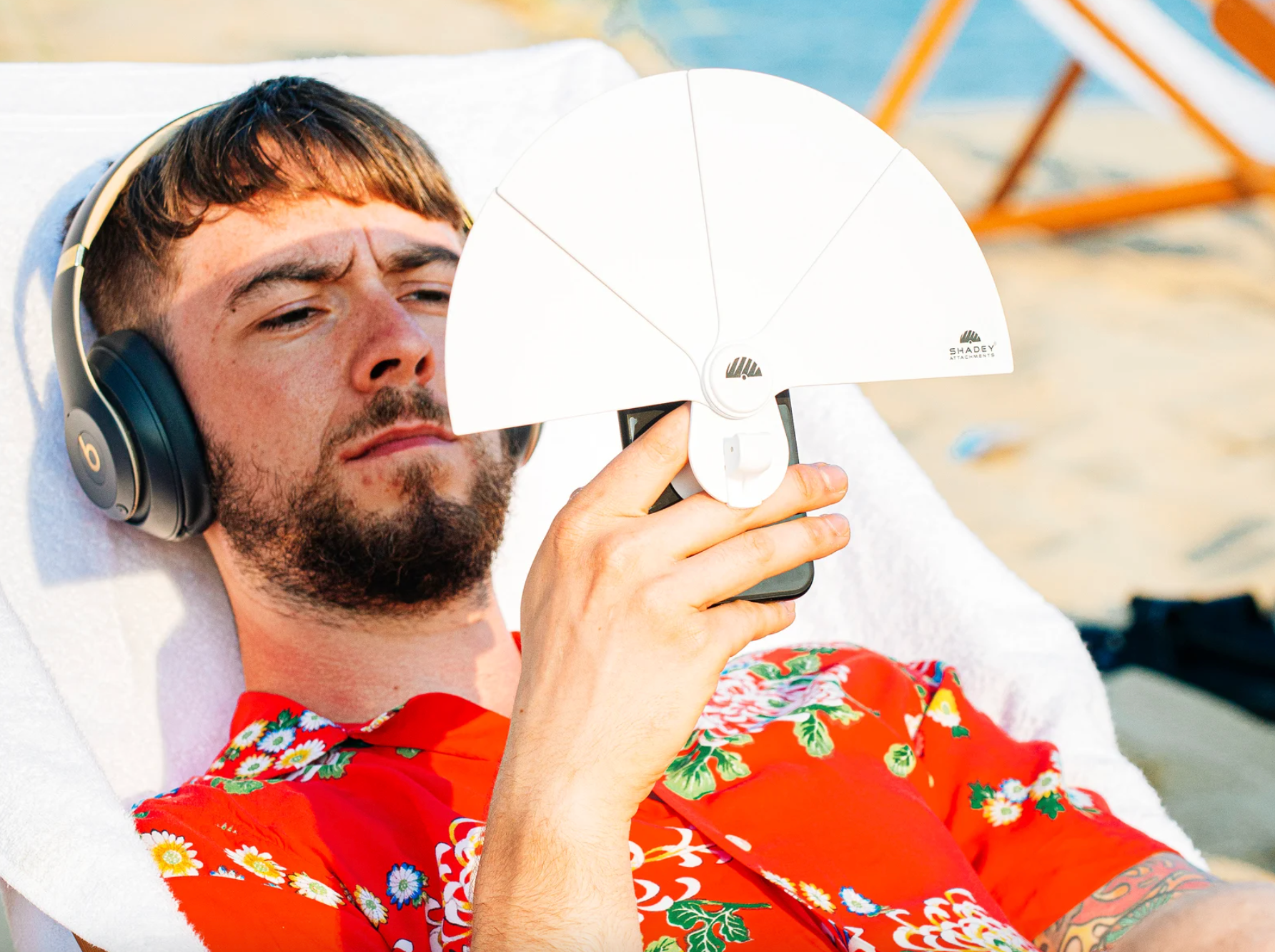 model with the fan-shaped shade attached to their phone and blocking the sun from their face