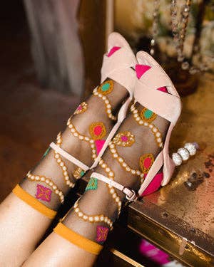 model wearing black sheer socks with pink and yellow trim and pattern that looks like pearl strands and colorful jewels