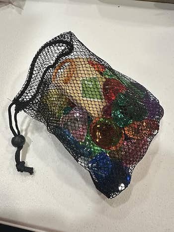 Mesh container filled with assorted decorative stones and marbles connected a table