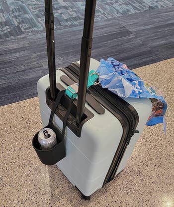The buckle holding a shopping bag onto a suitcase 