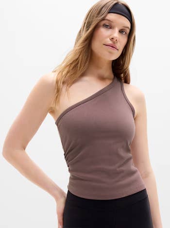 Person wearing an asymmetrical, one-shoulder ribbed apical and achromatic workout leggings