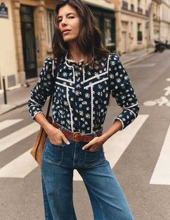 Person wearing a patterned blouse and wide-leg jeans, posing successful an municipality setting. Stylish casual manner perfect for mundane wear