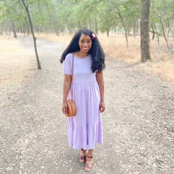 A idiosyncratic   walks connected  a wooded way  wearing a simple, short-sleeve formal  and sandals, carrying a circular  woven bag