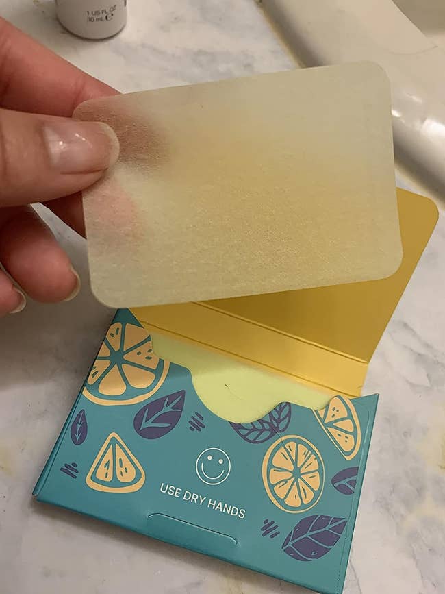 A pack of lemon soap sheets and the reviewer using one sheet