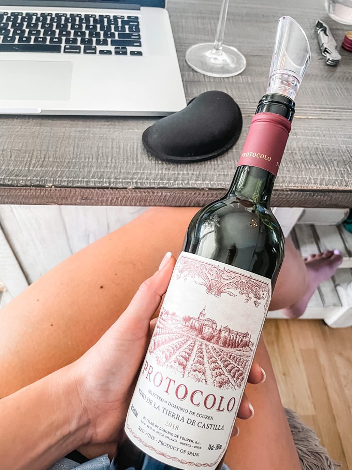 reviewer holding a wine bottle with an aerator on top