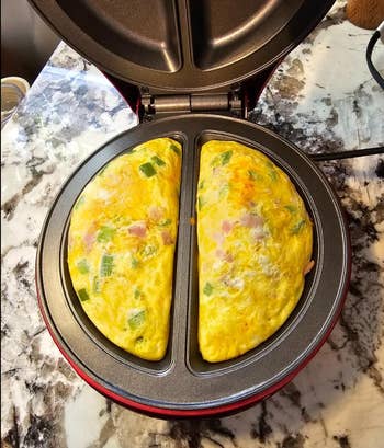 Omelets cooking in a red dual-sided omelet maker on a countertop