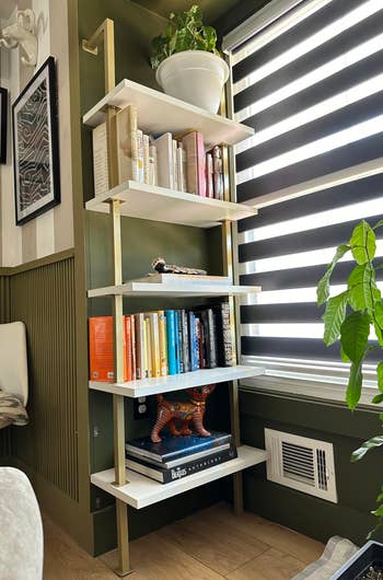 reviewer's gold and white 5-tier shelf holding plants and books