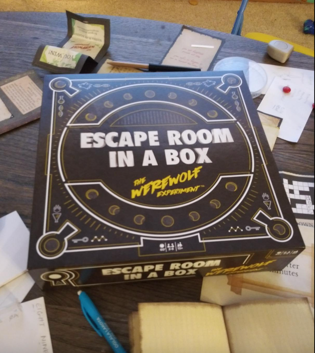 The escape room board game box with some contents of it laid out 