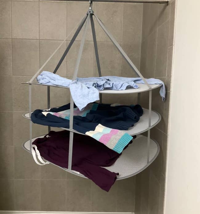 The rack, with three sweaters, on a reviewer's shower curtain rod