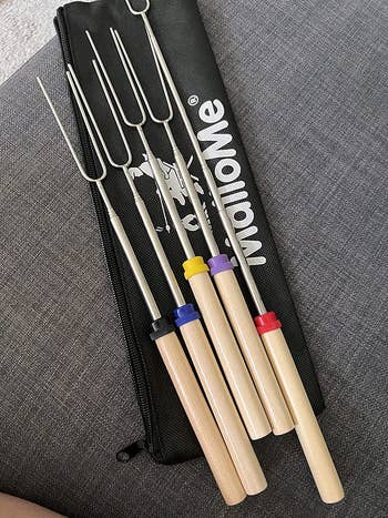 the marshmallow roasting sticks retracted next to the black storage bag, with each handle