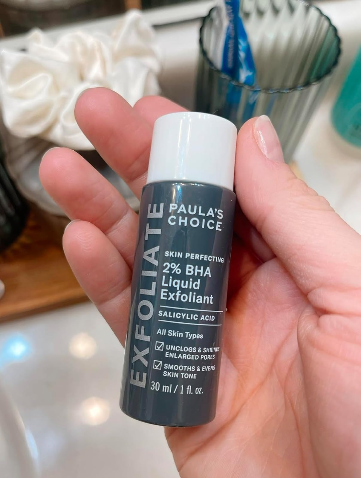 image of reviewer's hand holding small bottle of exfoliant