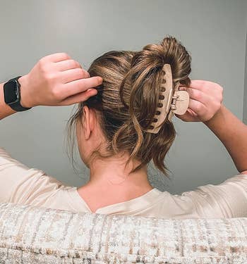 person securing their hairsbreadth with a ample khaki claw clip
