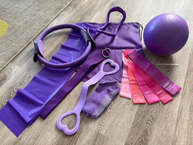 Purple Pilates and yoga acceptable   with workout  ring, absorption    bands, yoga socks, and shot  displayed connected  a woody  floor