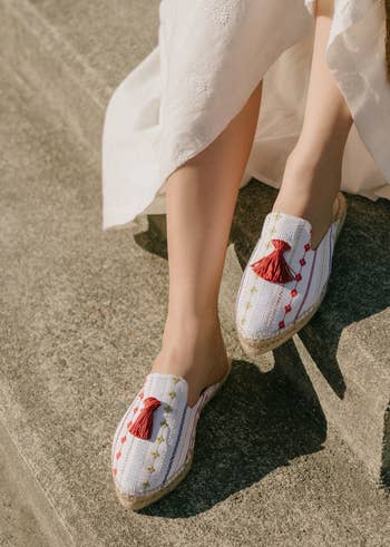 close-up of the espadrilles made of white cotton with cute red tassels