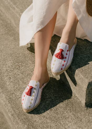 close-up of the espadrilles made of white cotton with cute red tassels