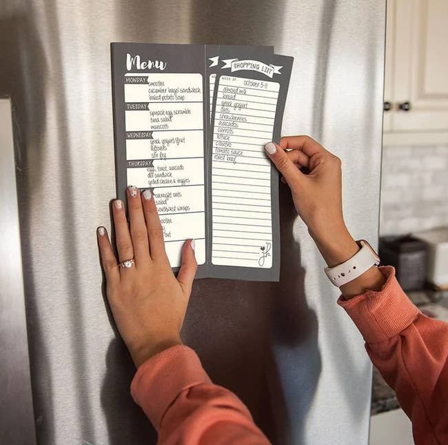 a model tearing the shopping list portion of the dual column notepad off as it hands on the fridge 