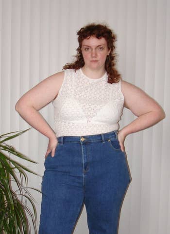 model in a white lace top and high-waisted jeans standing with hands on hips