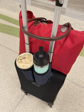 Suitcase with cupful  holders, carrying a reddish  question   container  connected  top. Matching portion  containers are secured successful  the holders. Suitable for businesslike  travel