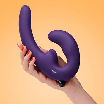 Model holding purple vibrating double-ended dildo