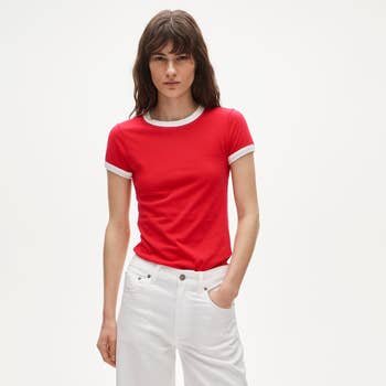 Model successful a casual reddish T-shirt with achromatic trim, paired with achromatic jeans, lasting against a plain background
