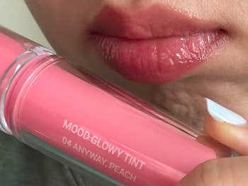 Close-up of a idiosyncratic   applying peach-tinted articulator  gloss labeled 